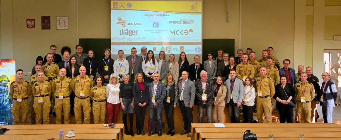 Liczna grupa uczestników konferencji na zbiorowym zdjęciu w audytorium