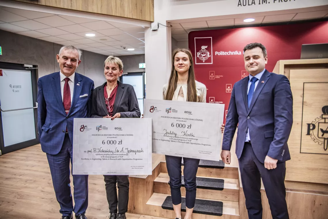 Dwie kobiety z czekami w ręku stoją pomiędzy dwoma mężczyznami