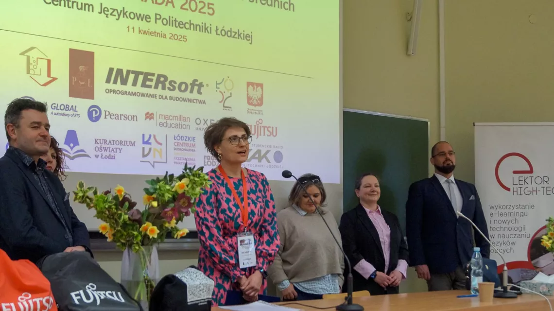 Kilka osób ztoi za stołem prezydialnym