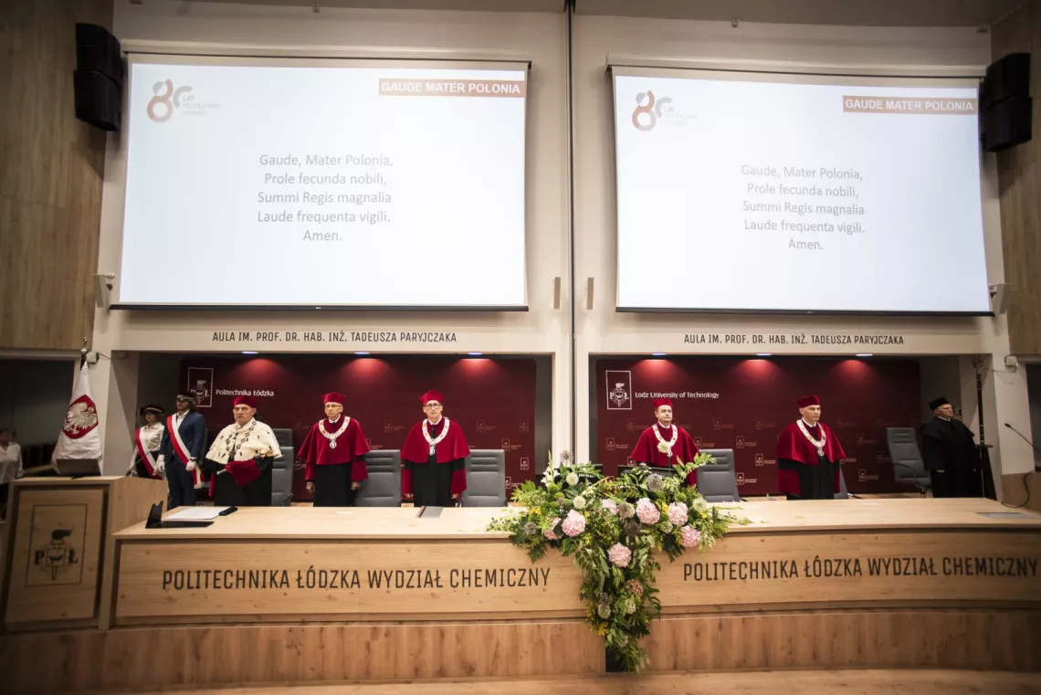 Rektor i prorektorzy stoją, nad nimi na ekranach wyświtlane są słowa Gaude Mater Polonia