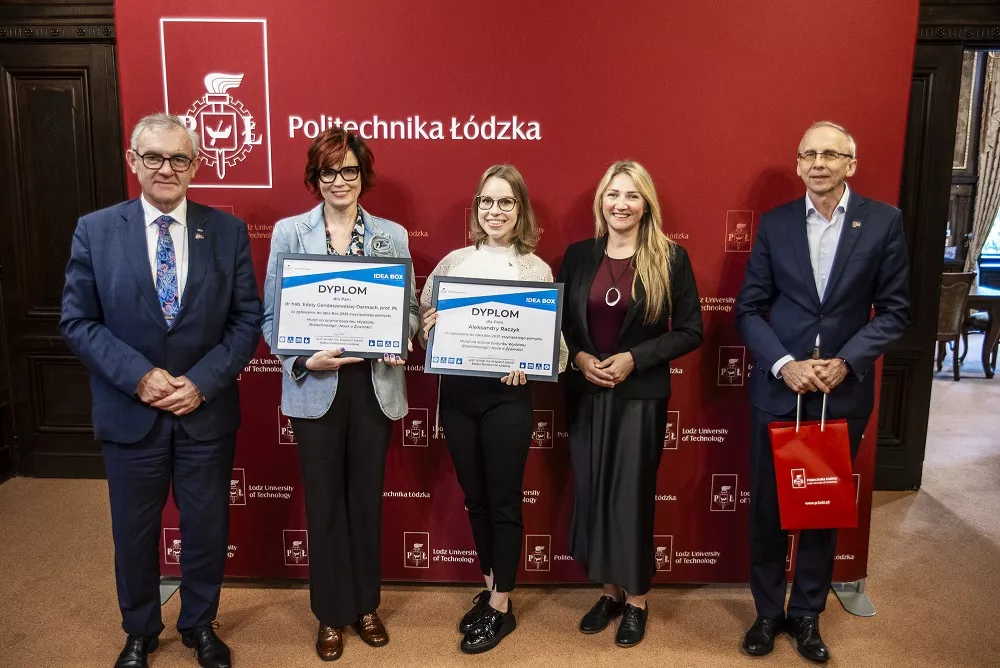 Trzy kobiety i dwóch mężczyzn stoją na tle bordowego baneru z napisem Politechnika Łódzka, dwie kobiety trzymają dyplom w rękach.