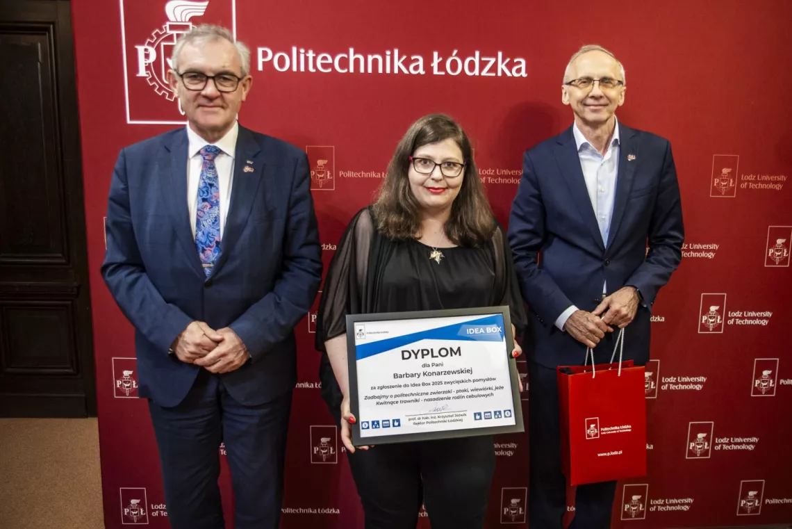 Kobieta tzymająca dyplom w towarzystwie dwóch mężczyzn, stoją na tle bordowego baneru z napisem Politechnika Łódzka