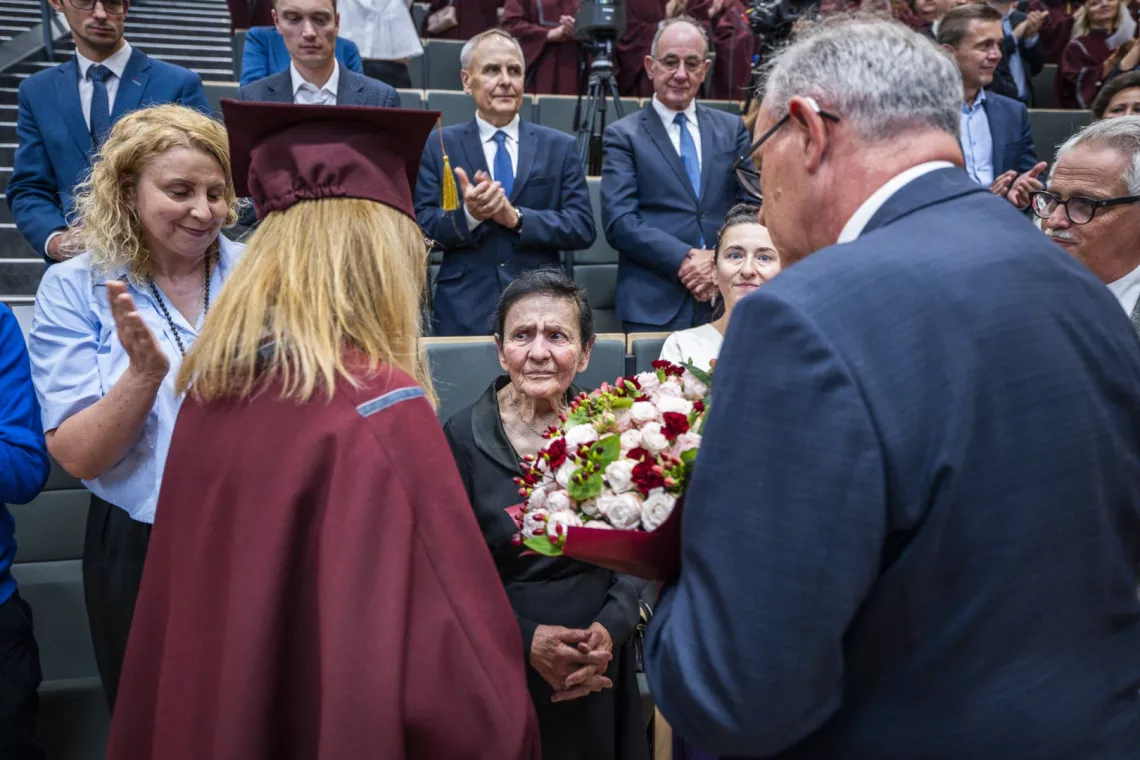 Małżonka, dr Halina Krysińska, orzymuje bukiet kwiatów z rąk dyrektor szkoły i rektora PŁ