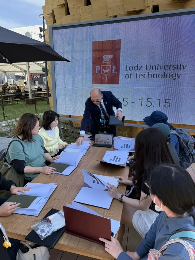 Mężczyzna prowadzi zajęci, za stołem uczestnicy trzymający skoroszyty z notatkami