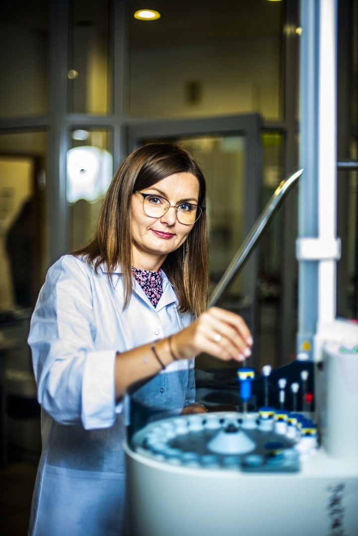 Chemiczka w laboratorium stoi przy aparaturze badawczej