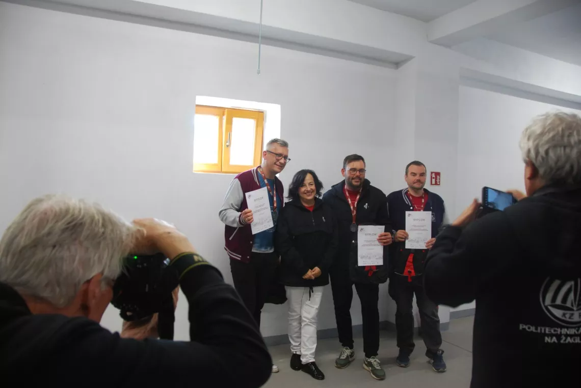 Cztery osoby - trzy z medalami i dyplomami pozują do zdjęcia