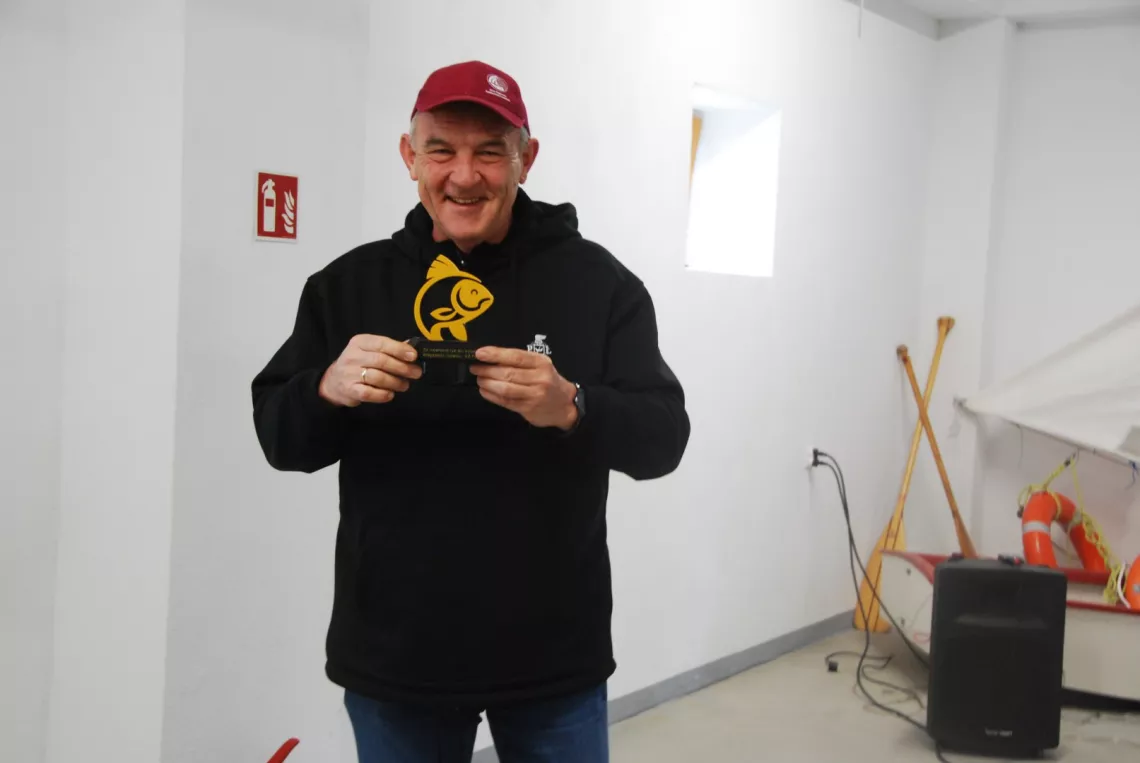 Uśmiechnięty mężczyzna ze statuetką w kształcie ryby