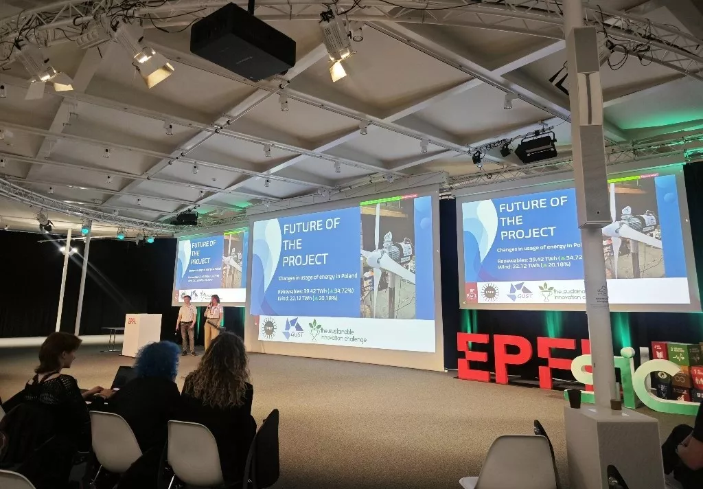 Prezentacja projektu przez dwie osoby, w tle ekrany z prezentacją