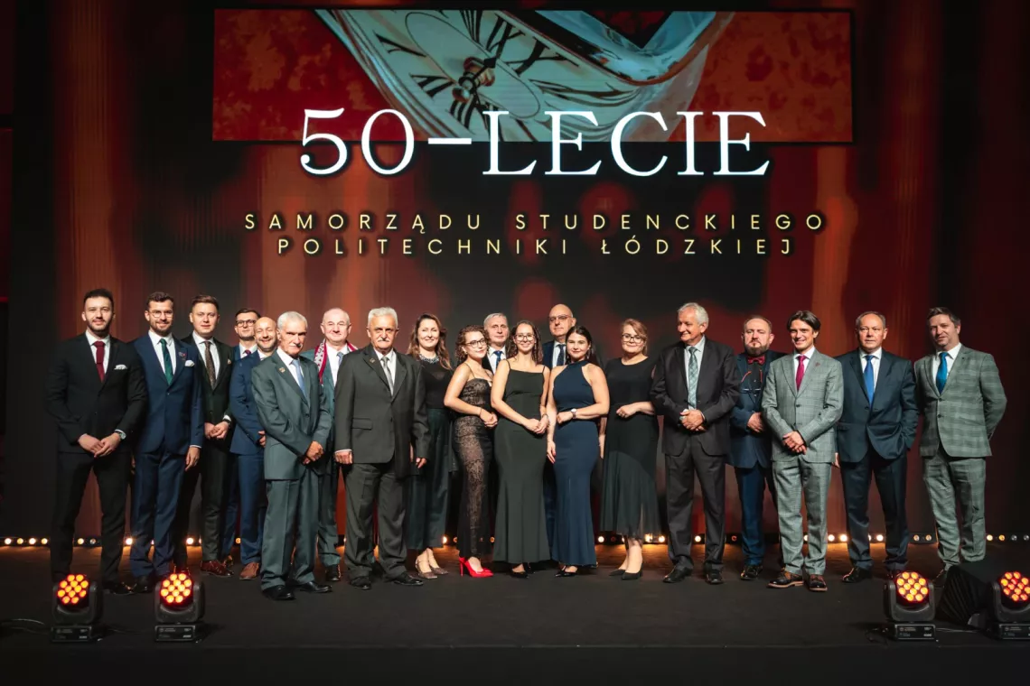 Kilkanaście elegancko ubranych osób pozuje do zdjęcia na tle napisu 50-lecie Samorządu Studenckiego Politechniki Łódzkiej