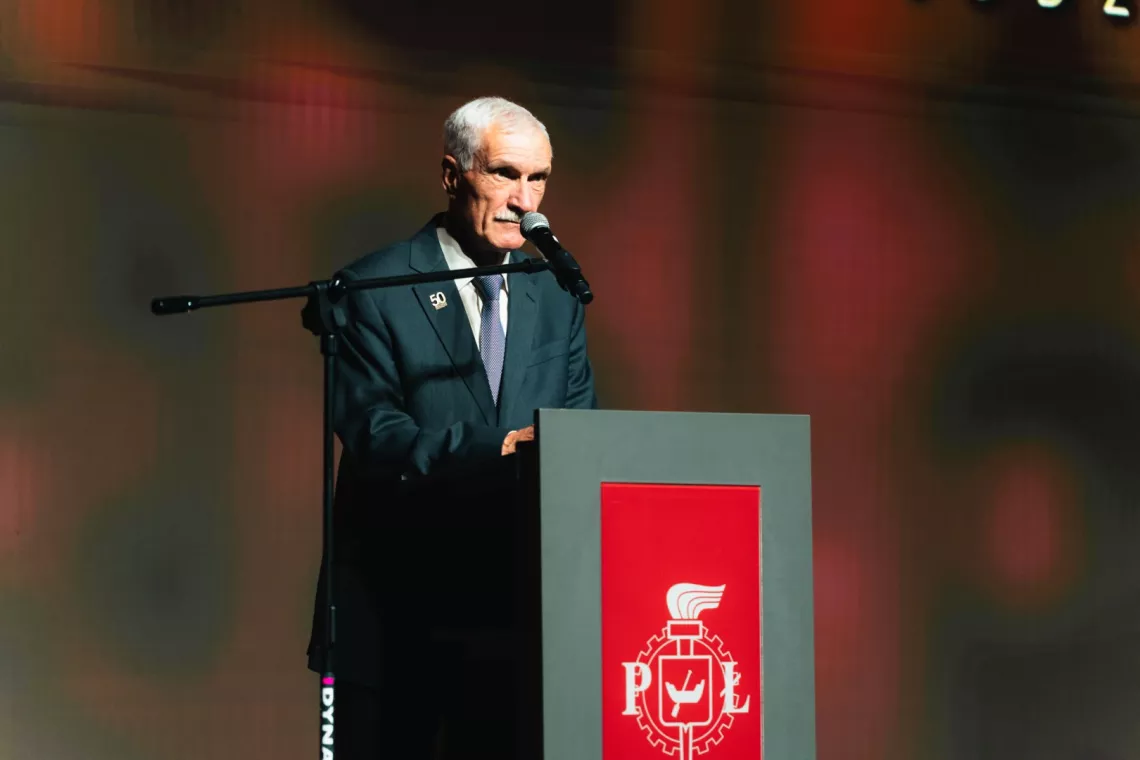 Mężczyzna przy pulpicie przemawiający do mikrofonu