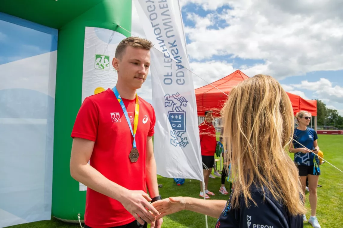 Kobieta gratuluje sportowcowi na podium z medalem