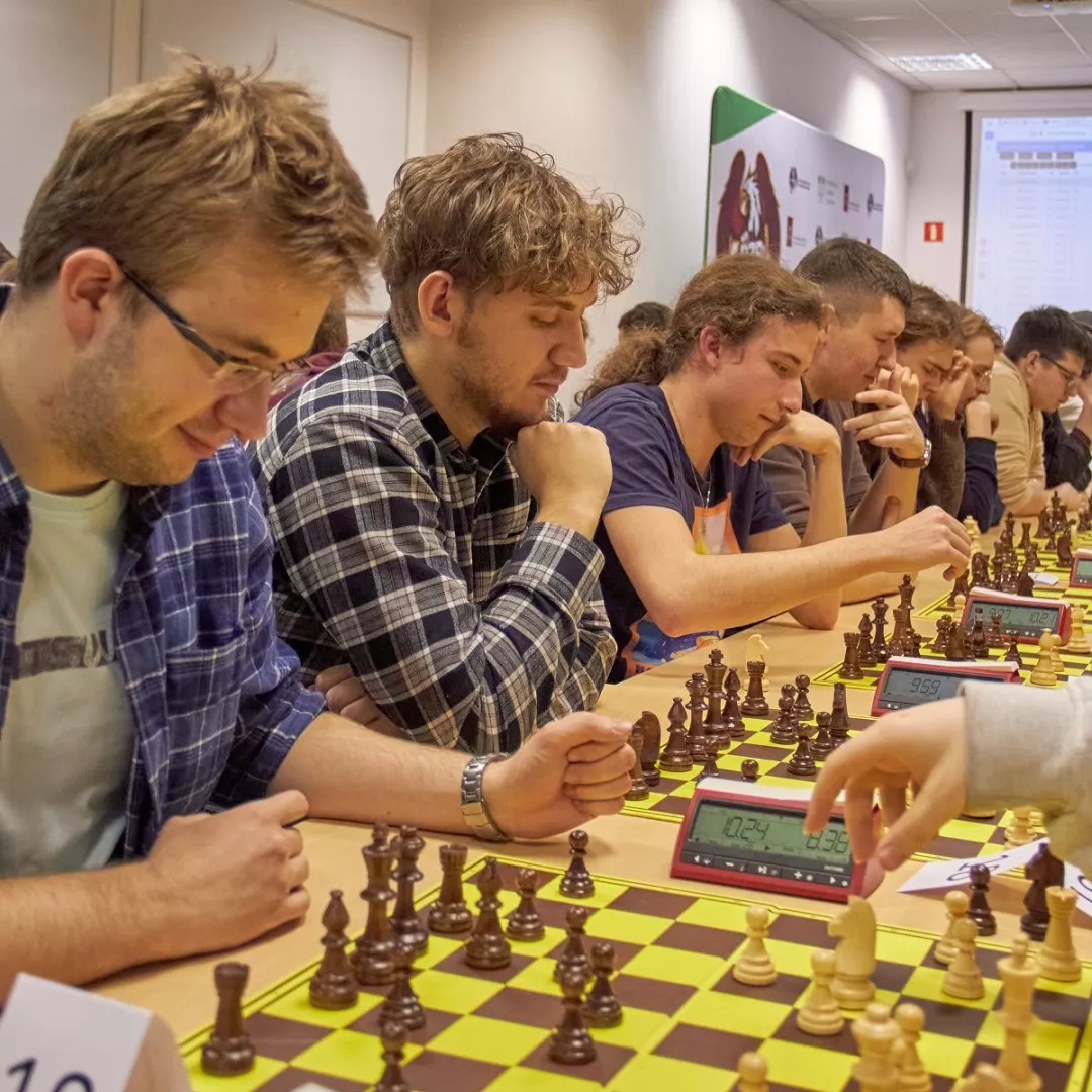 Uczestnicy głęboko skupieni podczas turnieju szachowego, z zegarami cyfrowymi śledzącymi ich ruchy