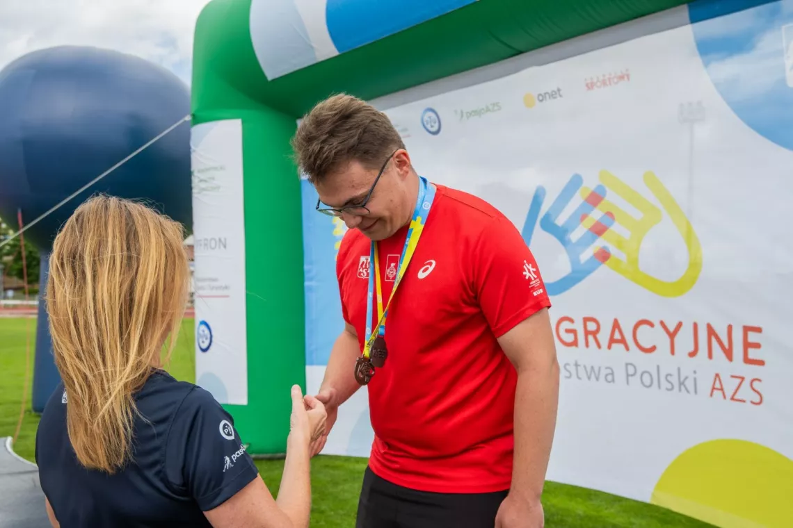 Kobieta gratuluje sportowcowi z medalem na podium