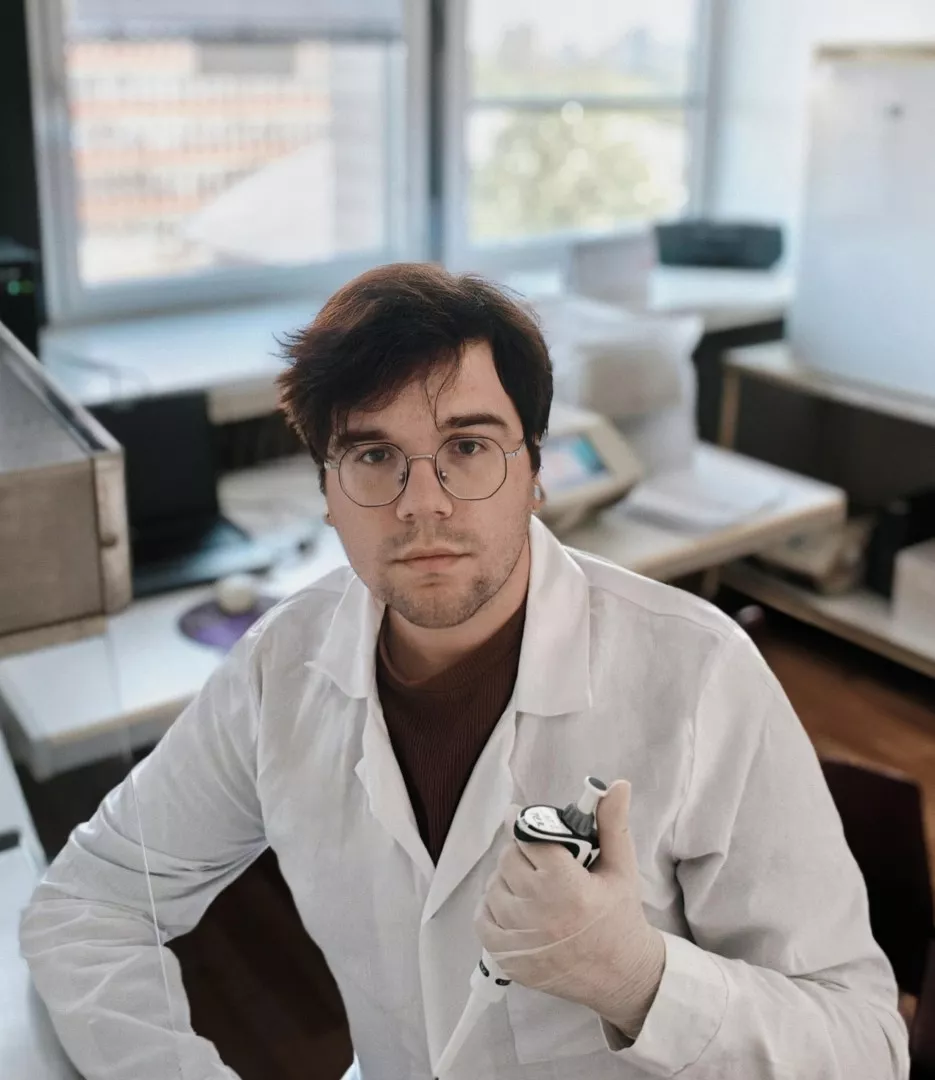 Młody człowiek w okularach i białym fartuchu w laboratorium