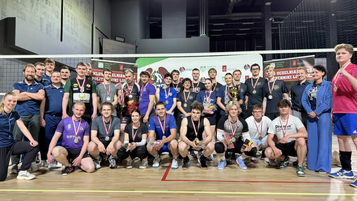 Bardzo liczna grupa sportowców z medalami pozuje do zdjęcia na boisku do gry w siatkówckę