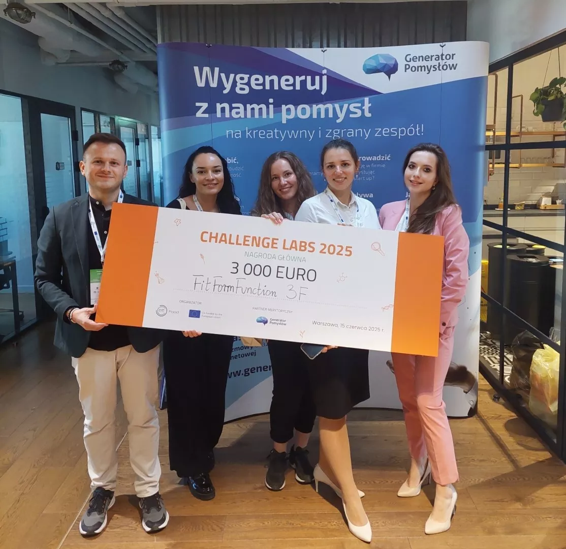 Mężczyzna i cztery kobiety trzymają czek z napisem Challenge Labs 2025, 3000 euro.  Stoją na tle rollupu z napisem Wygeneruj z nami pomysł. Generator pomysłów.