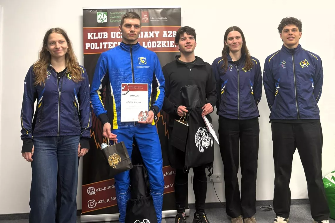 Pięcioro zawodników w sportowych strojach, jeden z nich trzyma w ręku dyplom. Z tyłu stoi rollup