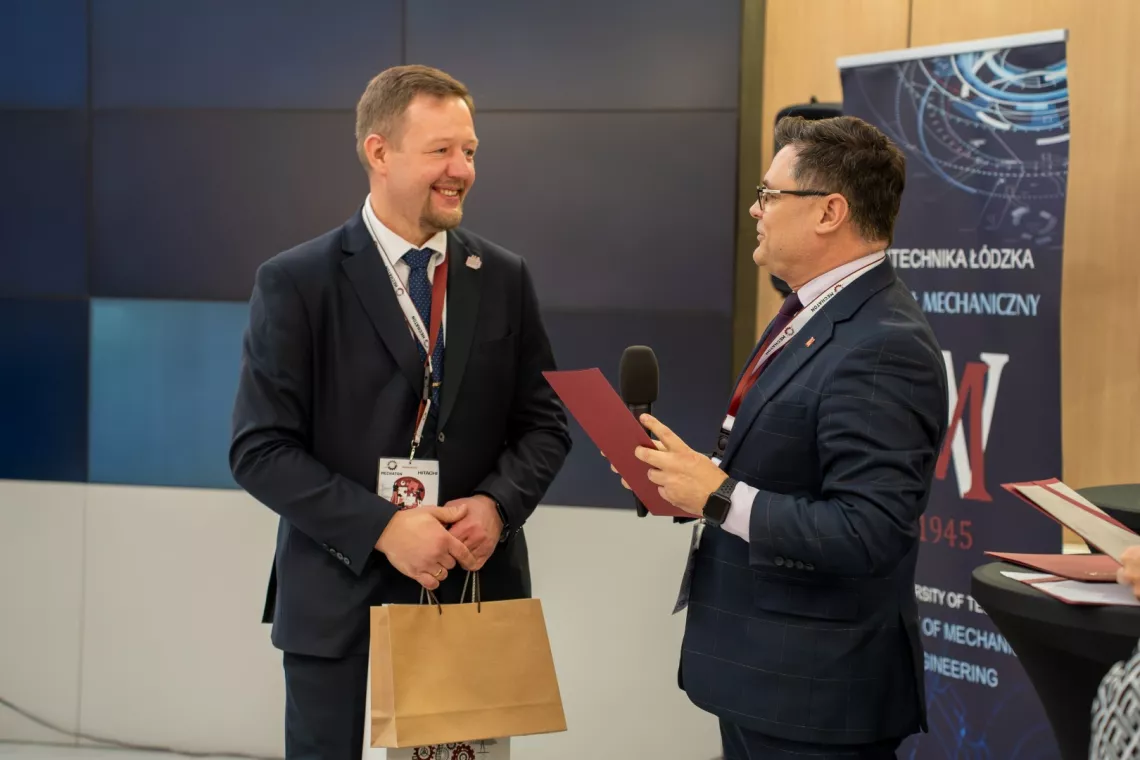 Dwóch mężczyzna rozmawia, jeden z nich trzyma mikrofon w ręku