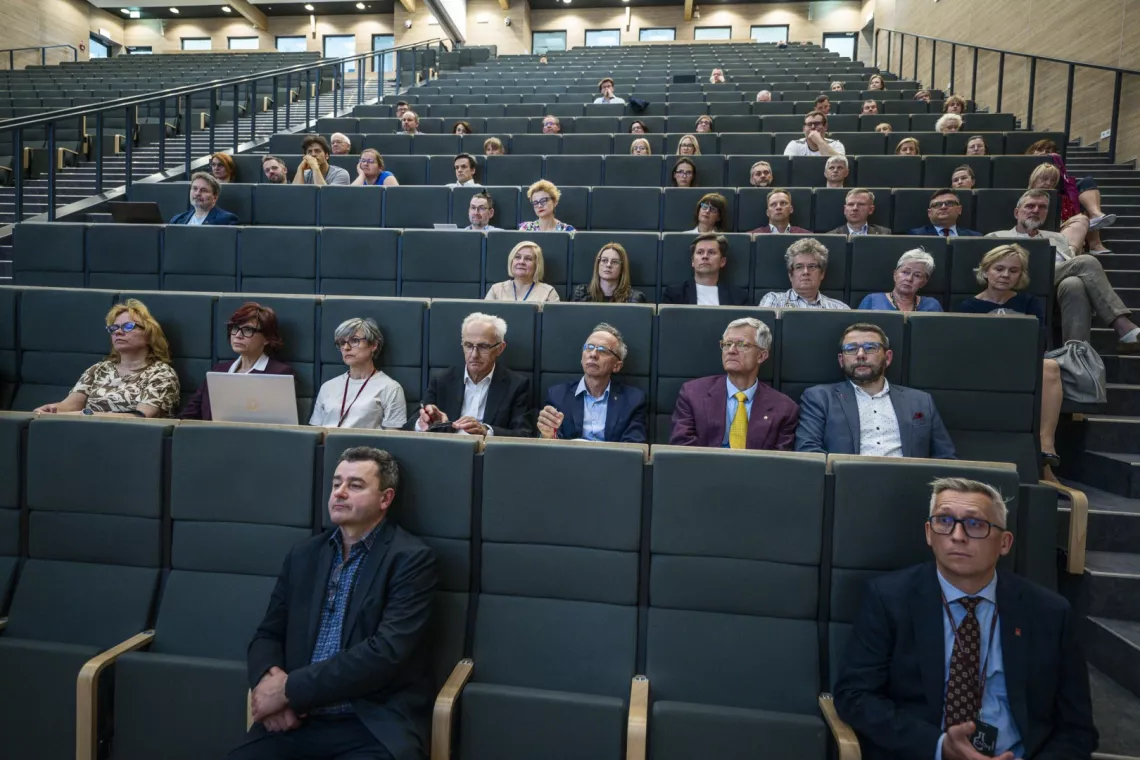 Grupa uczestników spotkania siedzi w audytorium.