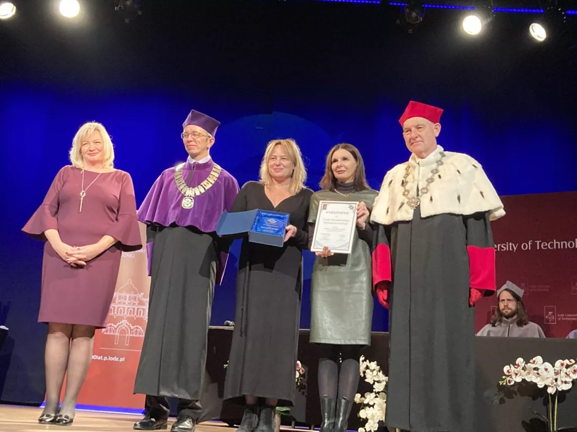 osoby na scenie z dyplomem i nagrodą oraz wręczający w togach