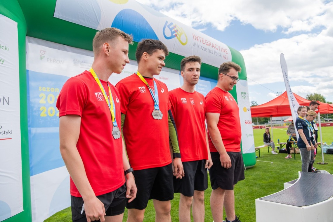 Czterech młodych mężczyzn w czerwonych koszulkach stoi z medalami 