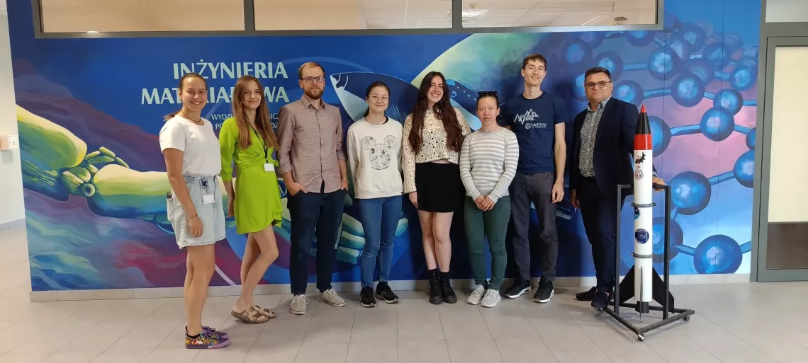 Grupa ośmiu osób na tle banera z napisem inżynieria materiałowa