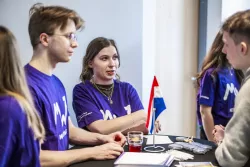 Kilka osób stoi przy stoliku i rozmawia