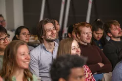 Grupa młodych osób siedząca w sali seminaryjnej słuchająca wystąpienia