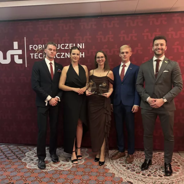 Pięcioro elegencko ubranych studentów na tle banera FUT