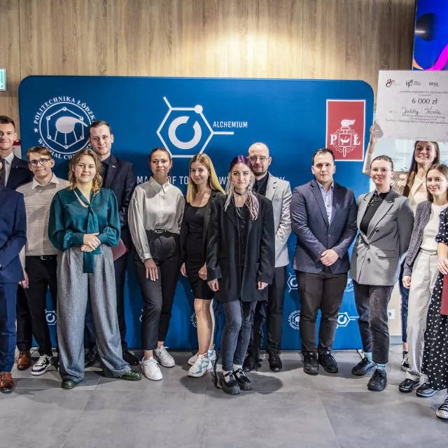 Grupa kilkunastu osób stojąca na tle ścianki reklamowej