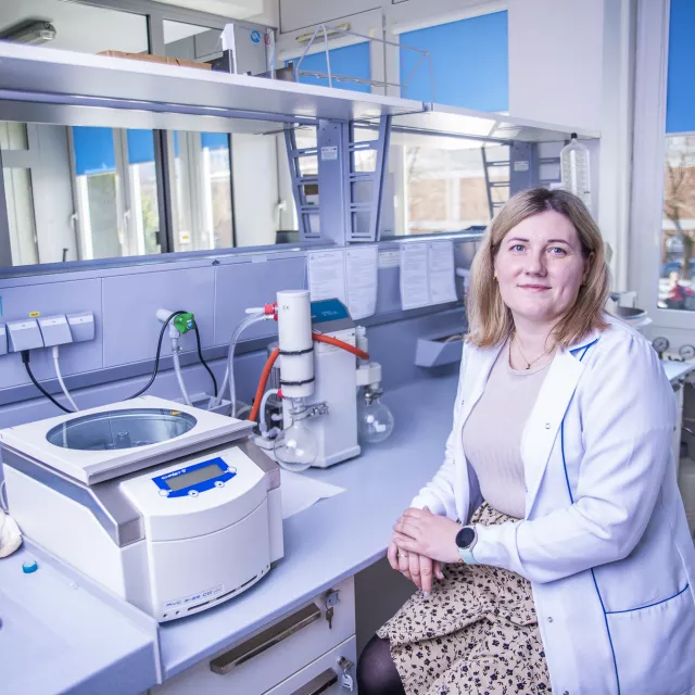 Osoba przy stole laboratoryjnym z różnym sprzętem.