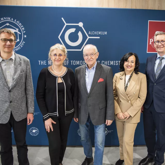 Pięć osób stoi na tle banera