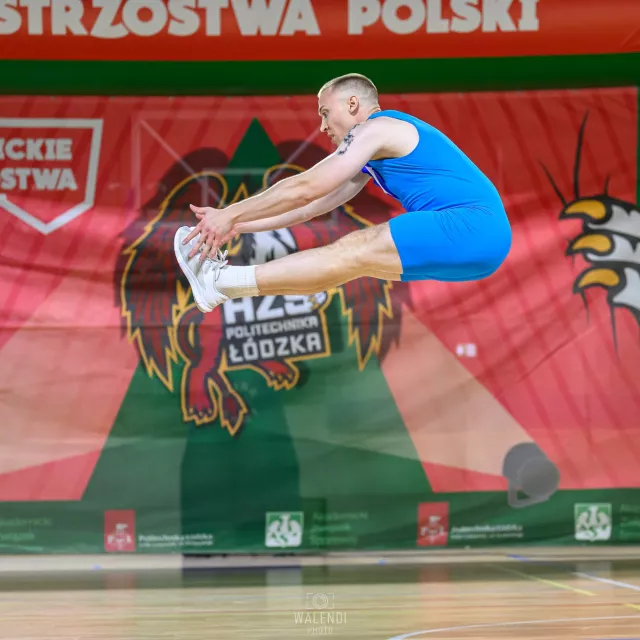 Sportowiec w niebieskim kostiumie wykonuje ewolucję w aerobiku