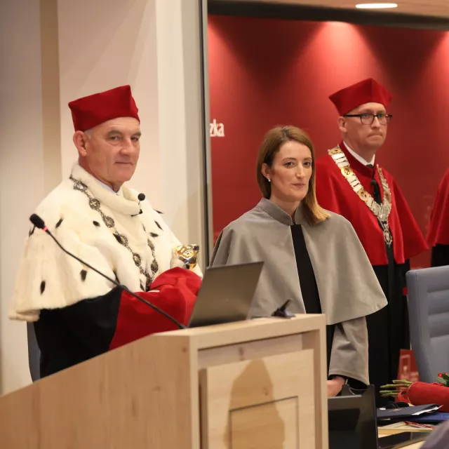 Osoby w togach stoją za katedrą audytorium