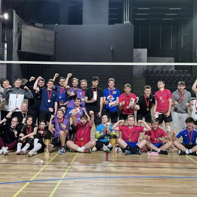 Liczna grupa sportowców stoi na sali do gry w siatkówkę