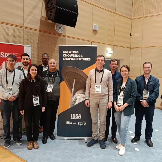 Dziewięć osób stoi przy rollupie z napisem creating knowledge, shaping futres