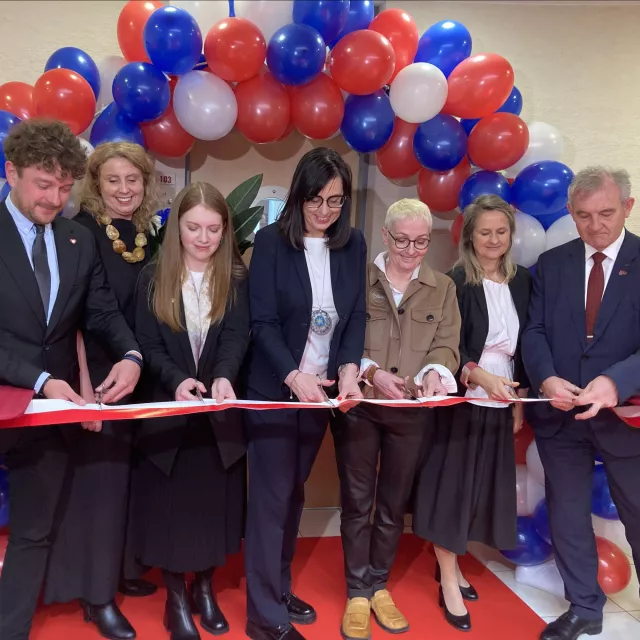 Osoby przecinające wstegę. Nad wejściem łuk z balonów.