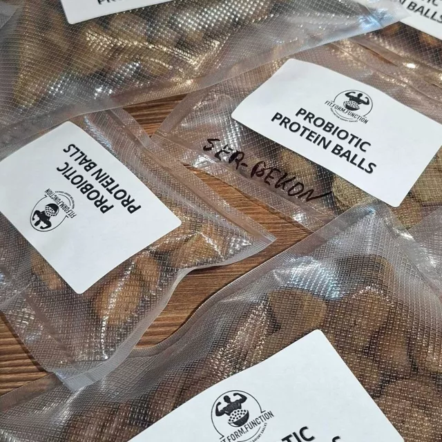 Opakowania z naklejką Probiotic Protein Balls, w których są brązowe kulki produktu