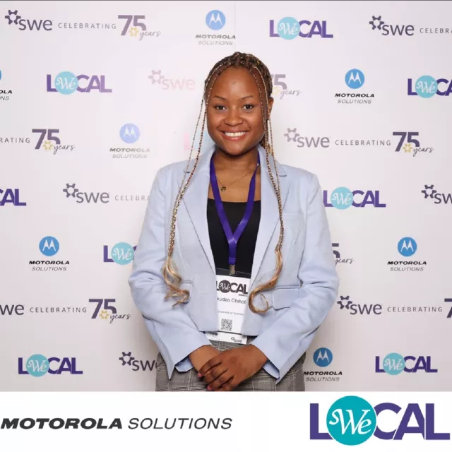 Dziewczyna w niebieskiej marynarce stoi na tle ścianki w różnymi logami