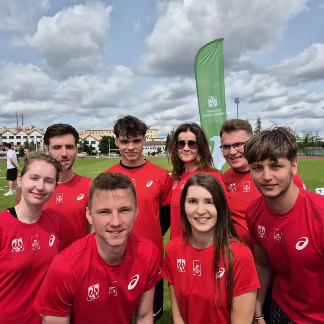 Sześcioro sportowców w czerwonych koszulkach z logo AZS stoi na boisku