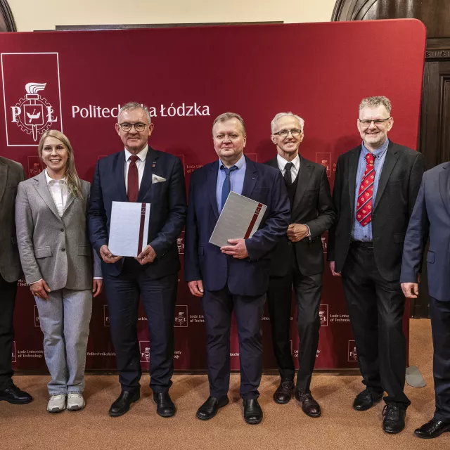 Uczestnicy spotkania na tle ścianki Politechniki Łódzkiej